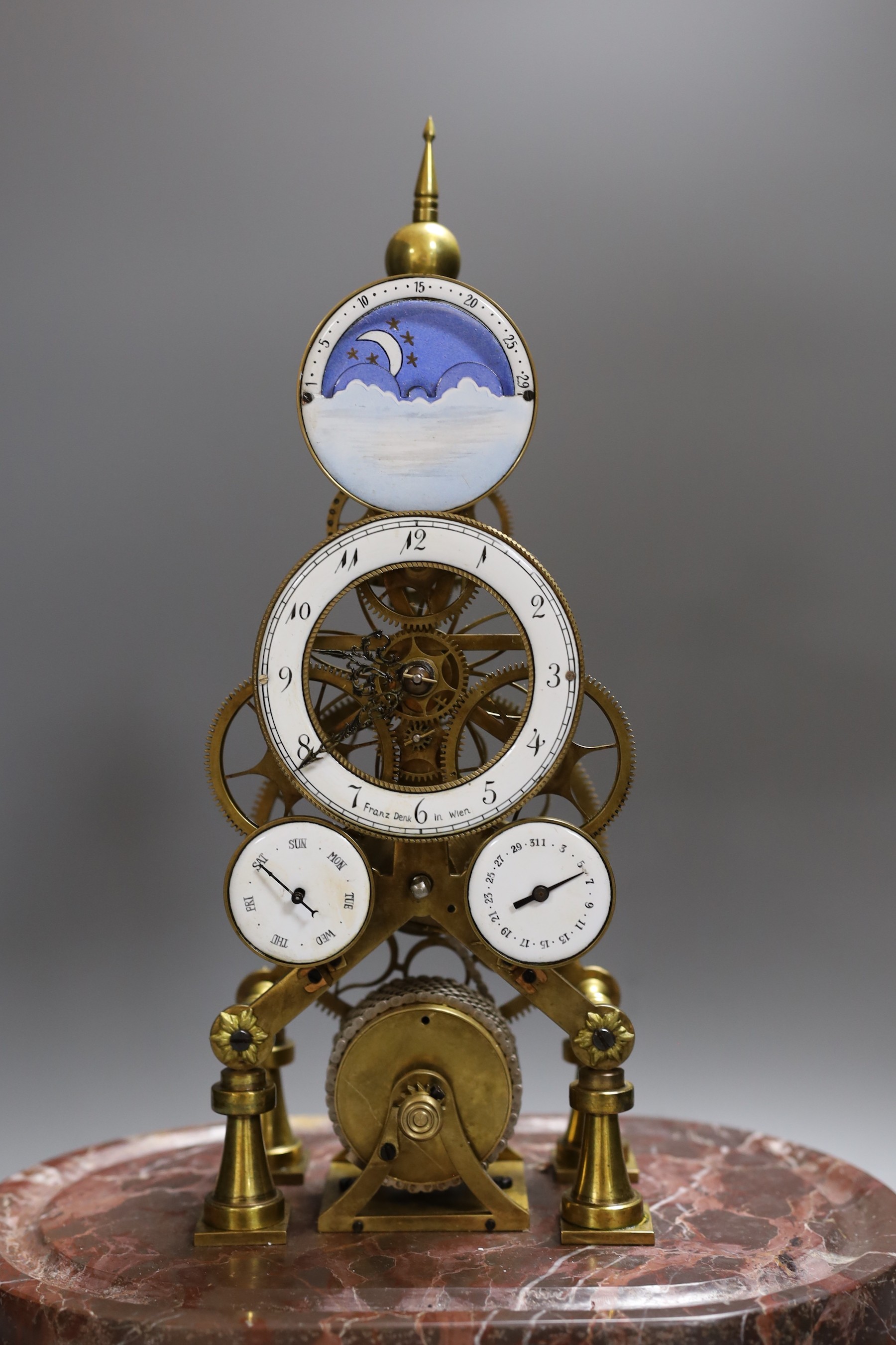 A calendar skeleton clock with moon phase dial, pin wheel escapement, dial signed Franz Denk in Wien, with pendulum, 50cm tall including dome